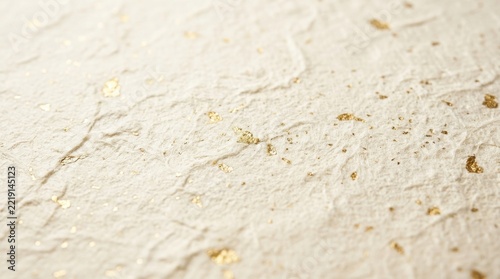 Elegant cream colored handmade paper texture featuring delicate gold leaf flakes scattered across a textured surface