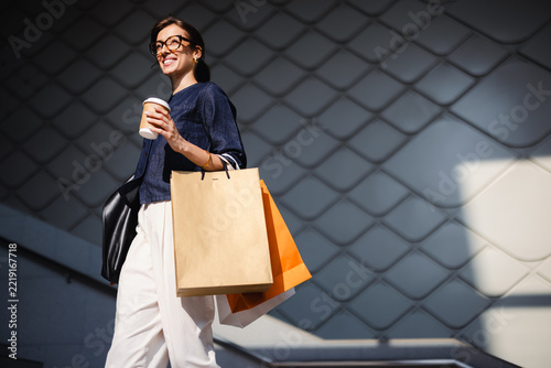 Young Woman Walks With Shopping Bags Outside a Modern Building