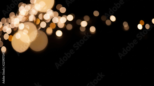 Abstract golden bokeh light circles on black background with copy space for festive celebration