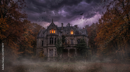 Mansion of gothic architecture stands abandoned in a misty autumn forest under a storm.