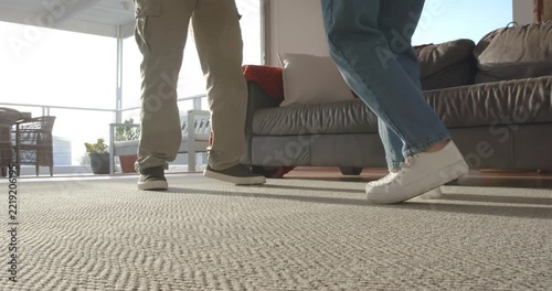 Lead foot is initiating coordinated footwork as two people are practicing dance steps on carpet