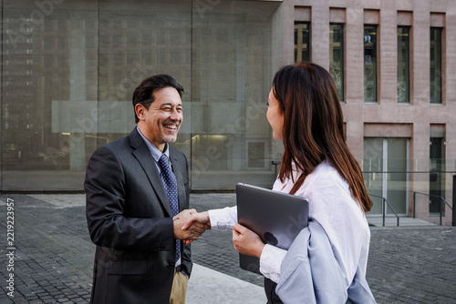 couple of Adult Hispanic Business Woman and man shaking hands Outdoors in winter at morning outdoors in street city