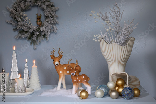 Christmas shelf decoration with deer figurines wreath baubles and silver candles on blue wall