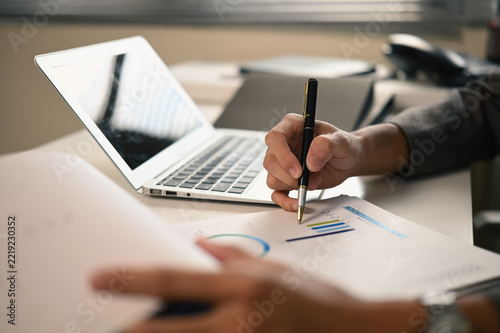 Cropped Hands of Business Person Analyzing Financial Charts with Pen and Laptop on Office Desk