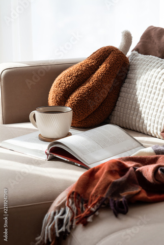 Cozy relaxation scene with book and coffee on sofa warm autumn blanket autumn pillow