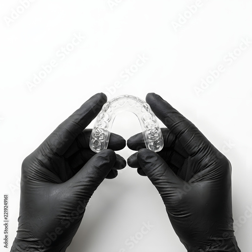 Dentist holding clear plastic dental aligner tray for teeth