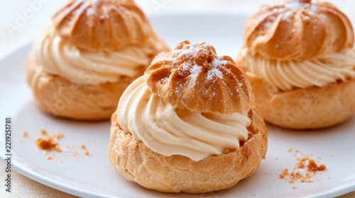 Three delicious cream puffs filled with vanilla chantilly cream on a white plate, close-up shot