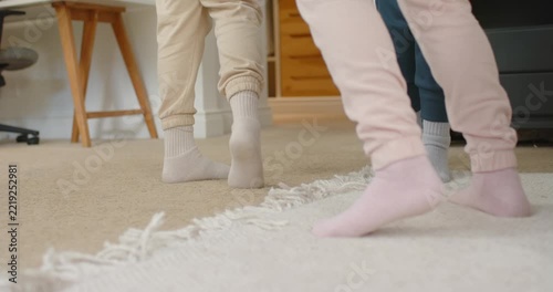 Three socked feet are shifting weight, initiating stepping, pivoting on fringed rug by bed playing