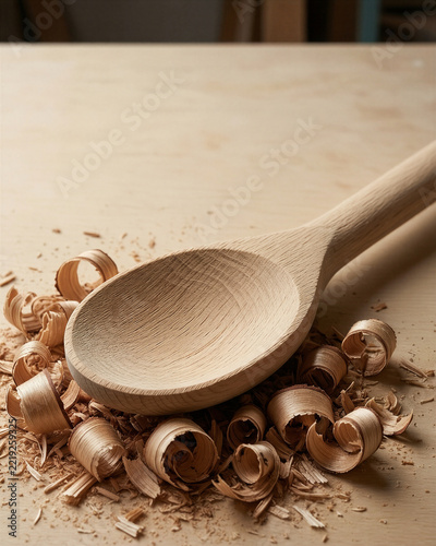 A hand carved wooden spoon resting in fine shavings