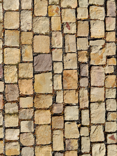 Close-up view of an ancient stone wall with irregularly shaped stones, moss, and natural weathering patterns, showcasing rustic texture and historical charm.