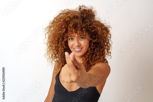 Hispanic woman with curly brown hair smiling and making a hand gesture