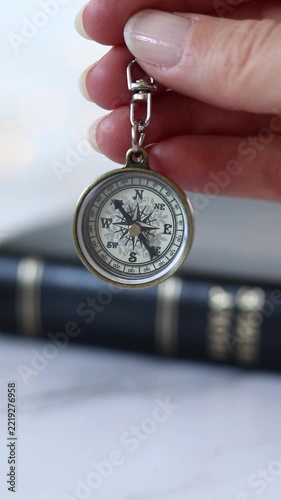 Ancient pocket compass in hand with holy bible in the background. Vertical video.