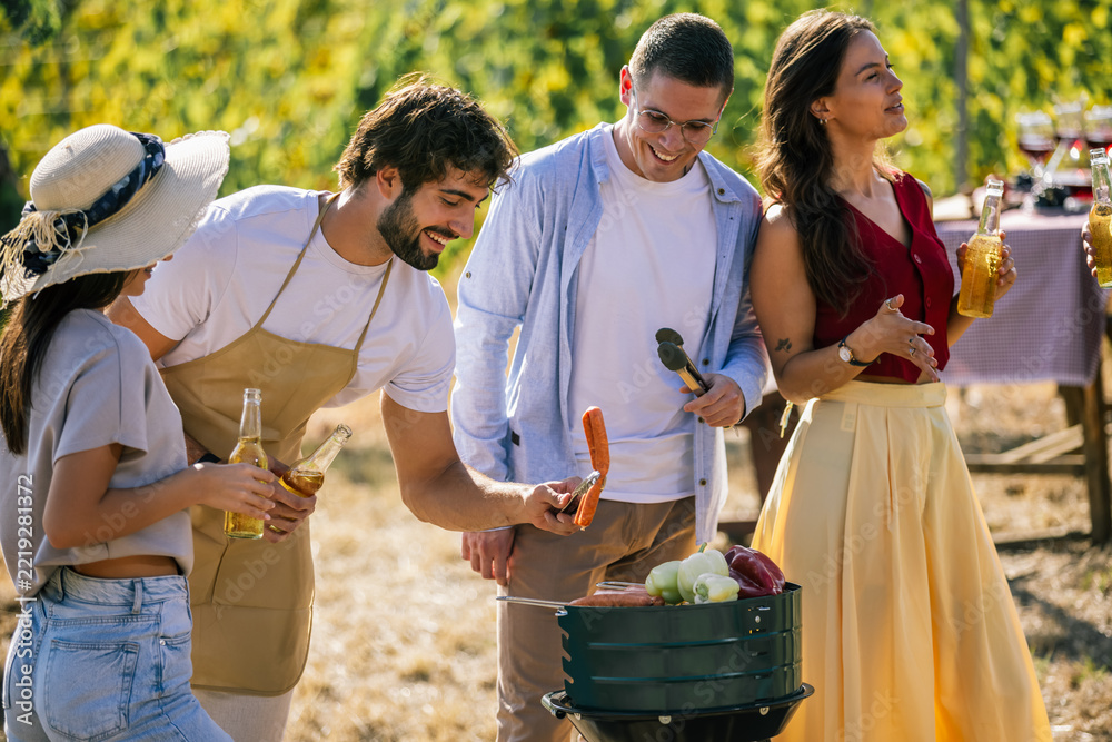 Naklejka premium Friends preparing grilled food together during a vineyard gathering