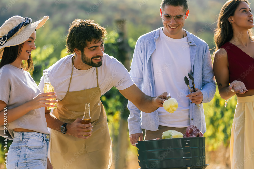 Naklejka premium Friends cooking together and sharing drinks in a sunny vineyard