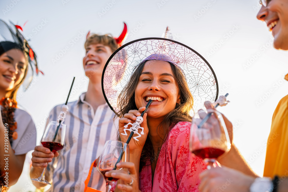 Naklejka premium Woman in Halloween witch costume smiling among friends outdoors