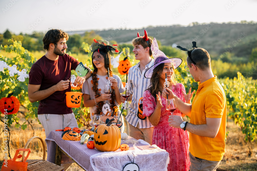 Fototapeta premium Friends in colorful Halloween costumes celebrating in a vineyard