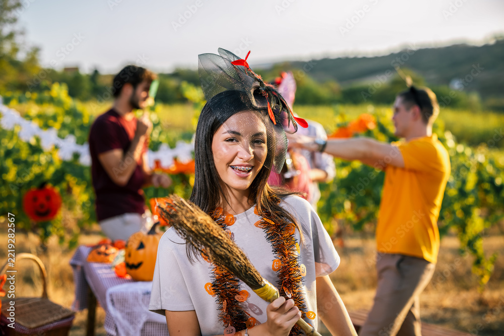 Fototapeta premium Woman in Halloween costume smiling with friends at a vineyard party