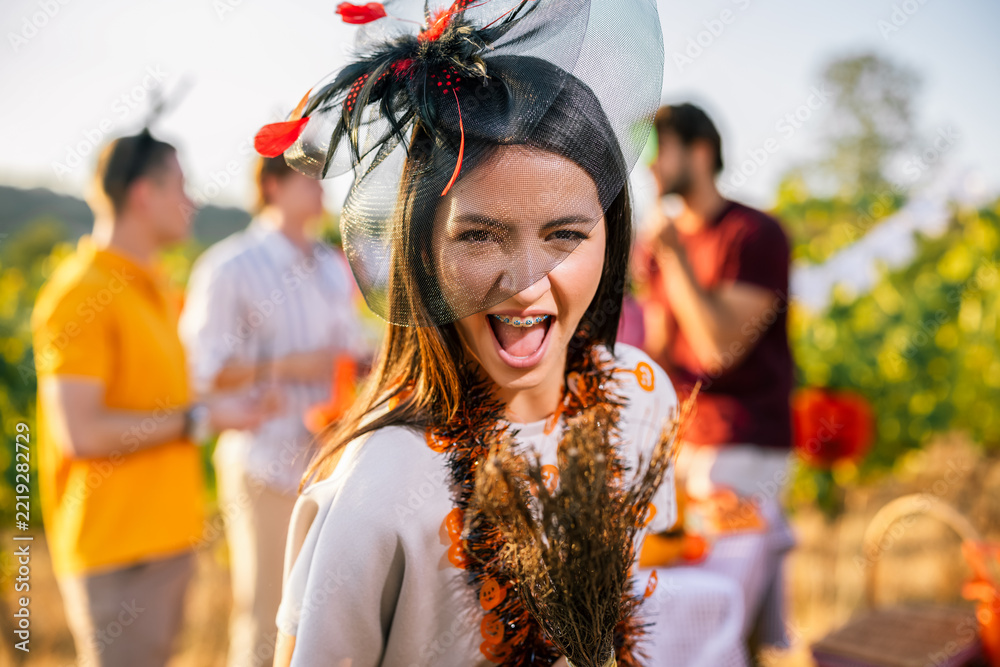 Fototapeta premium Excited woman in Halloween costume holding a decorated broom outdoors