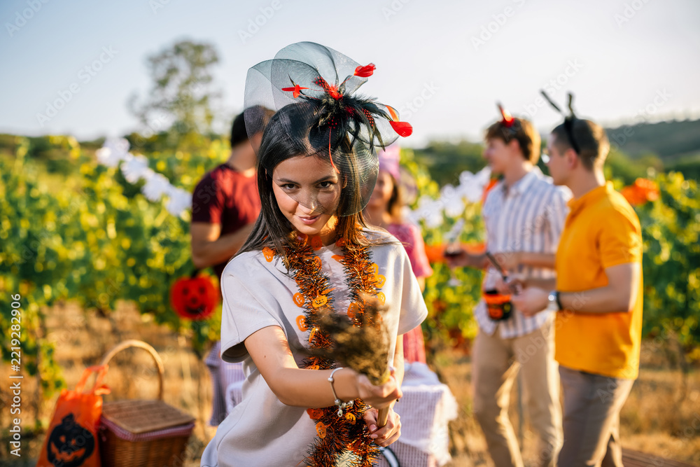 Fototapeta premium Woman carrying a broom while celebrating Halloween with friends in a vineyard
