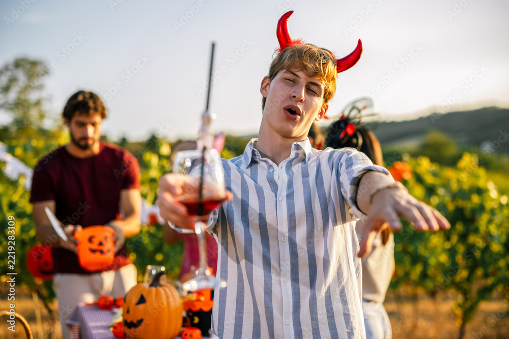 Fototapeta premium Man wearing devil horns reaching toward the camera at a Halloween party