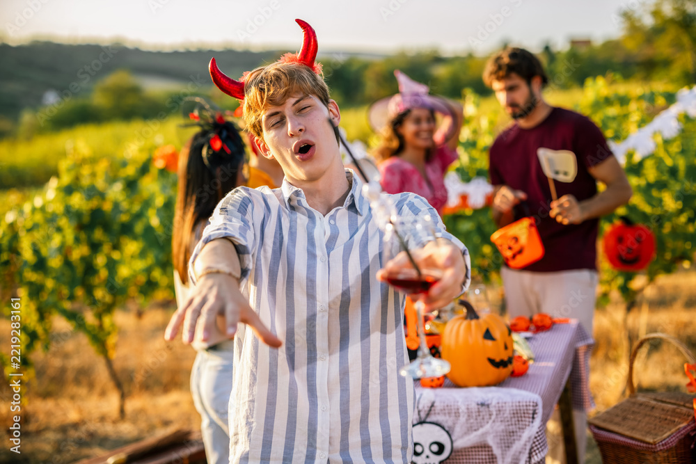 Fototapeta premium Man in devil horn costume gesturing during a Halloween vineyard celebration
