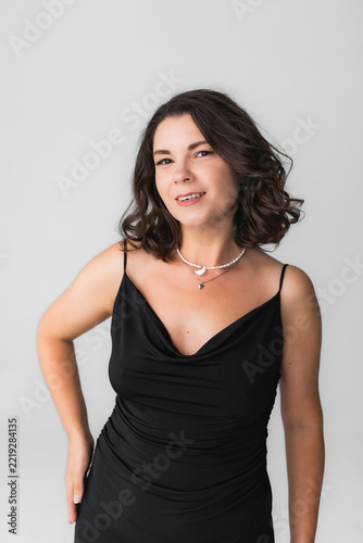Portrait of radiant forty year old woman in black evening dress smiling confidently.