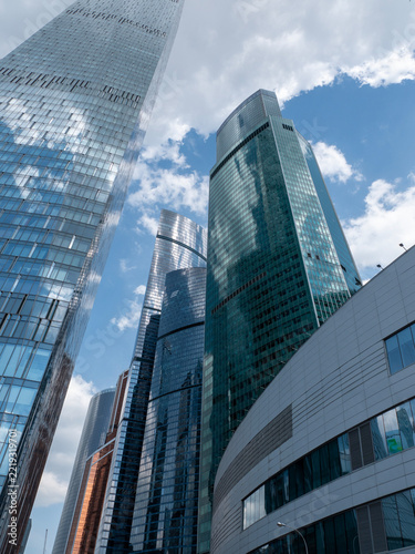 Modern glass skyscrapers with reflective facades rising against a clear blue sky in an urban setting