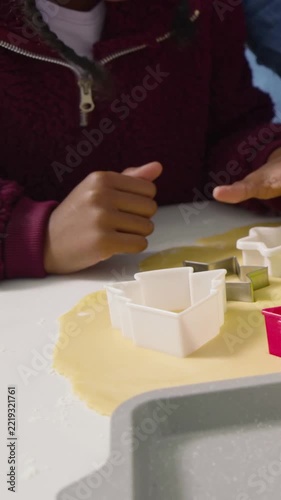 Vertical video: Reaching kid maroon zip cutting dough using star cutter, blue arm aiding