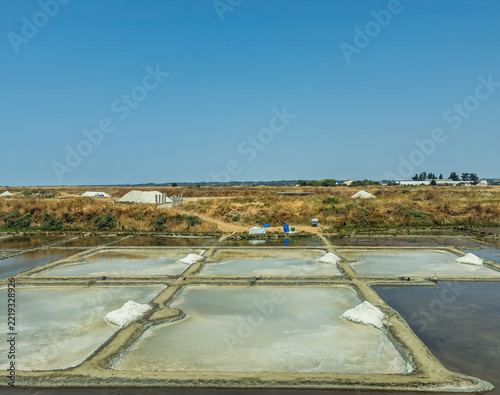 Obraz na plátně Le Croisic, France, Europe - August 14, 2026: Flat landscape of ocean wetland where sea salt it harvested in shallow, controlled ponds under a light blue sky