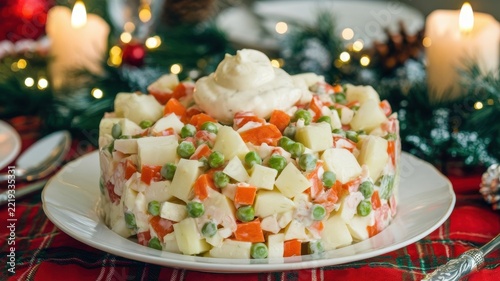 Russian cuisine. Olivier salad. A New Year’s salad made of chopped vegetables is arranged in a shape on a plate and garnished with mayonnaise.