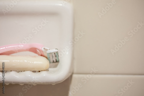 Reusable Shaving Razor and Bar of Soap on Ceramic Soap Dish in Bathroom