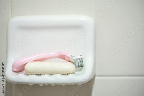 Pink Reusable Shaving Razor and White Soap on Ceramic Bathroom Dish
