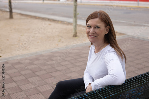Smiling Mature Woman Sitting on a Park Bench Outdoors