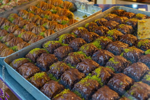 Rows of golden, syrupy baklava with pistachio garnish displayed in metal trays