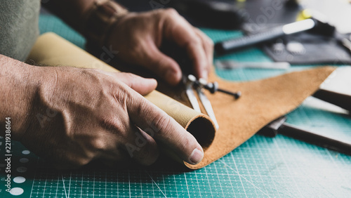 Artisan marking lines on natural leather using a leatherworker's compass.