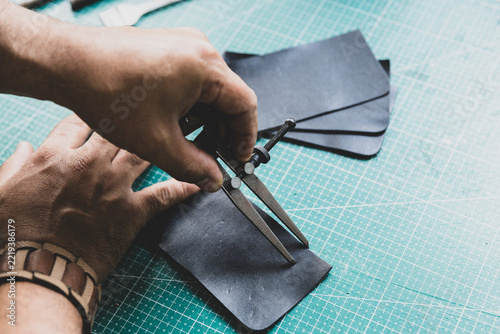 Artisan marking lines on natural leather using a leatherworker's compass.