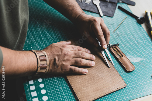 Artisan marking lines on natural leather using a leatherworker's compass.