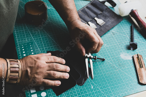 Artisan marking lines on natural leather using a leatherworker's compass.
