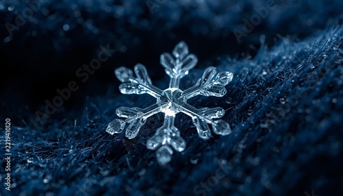 Macro photo of a single detailed snowflake ice crystal on dark blue wool fabric