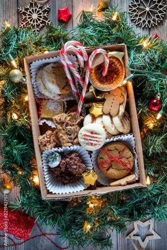 A box filled with a variety of Christmas baking surrounded by greenery.