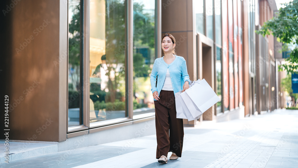 Fototapeta premium Young adult asian woman holding shopping bags in city shopper duty free