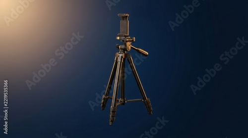 Modern black tripod with smartphone holder mount, portable camera stand for video recording, photography equipment on dark studio background