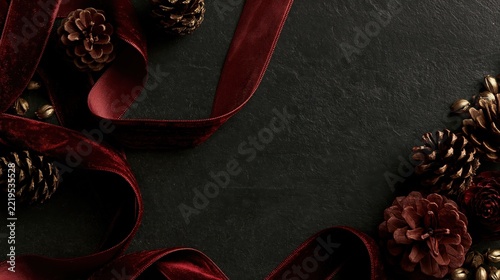Velvet ribbon and pinecones arranged on a dark textured surface during winter holidays