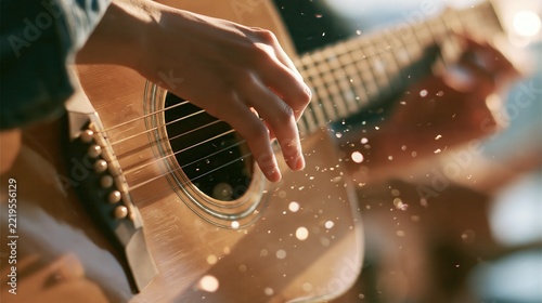 Close-up of hands playing an acoustic guitar with golden bokeh during a sunset