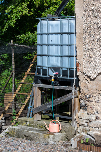 Cubic tank with rain water near barn