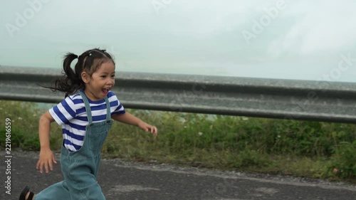 slow motion of preschool child girl running on a road on mountain in the morning