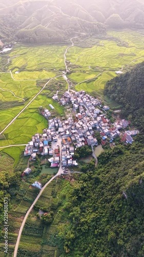 Vertical Video: Aerial view of a high-speed rail bridge crossing through green farmland and rural villages.