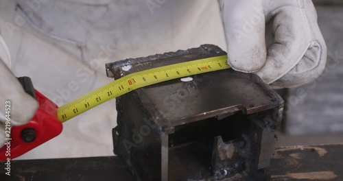 Close up view of worker hands in white gloves measuring metal object with tape measure