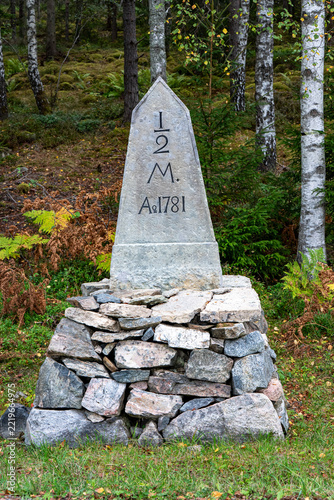 Old historical mile post made from stones near road