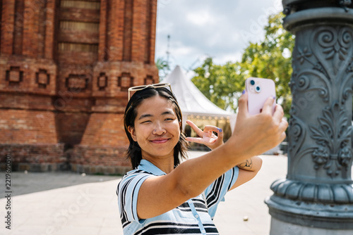 Young woman taking selfie with peace sign in barcelona